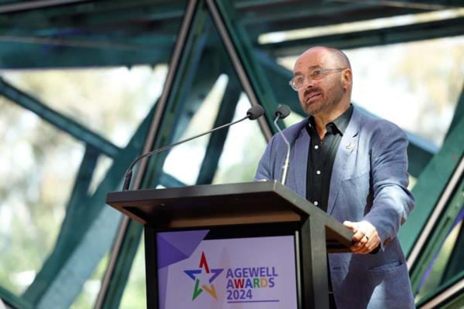 Person on stage giving speach behind lecturn.