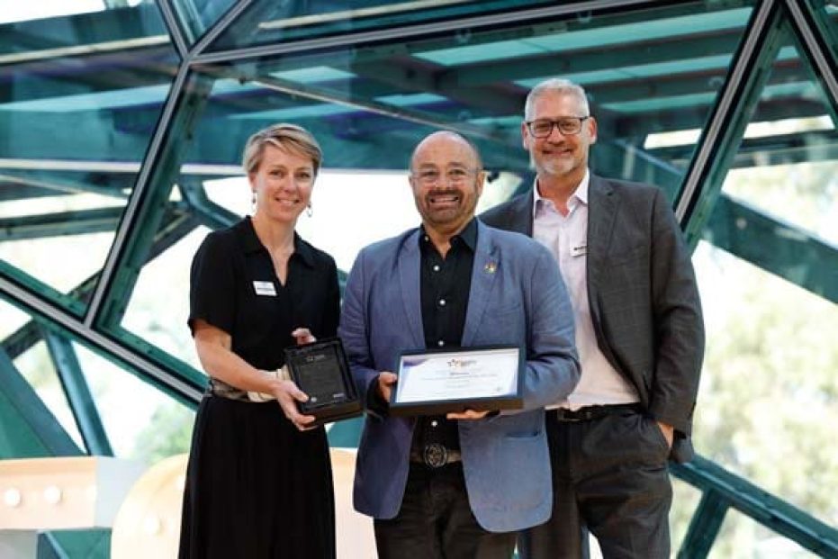 Three people on stage with certificate.