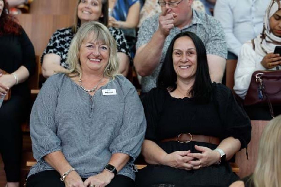 Two people sitting and smiling.