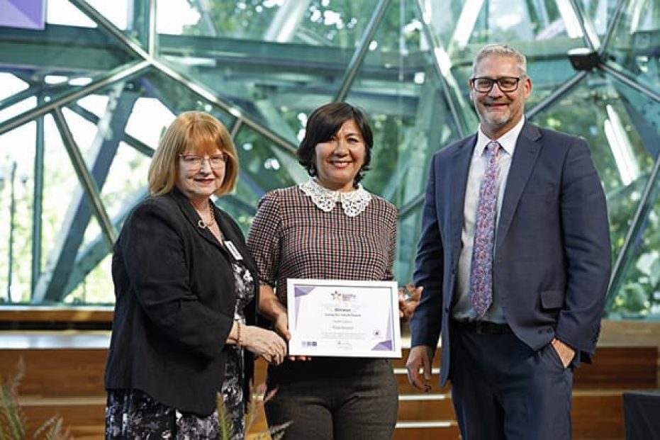 Three people on stage with certificate.