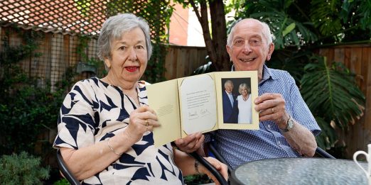 Two people sitting in garden holding a photo album.