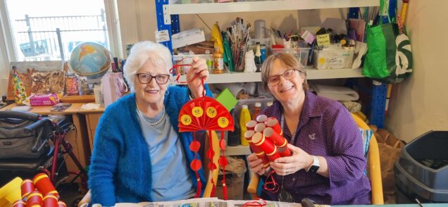 Two people are photographed making Chinese lanterns
