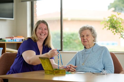 Resident Valda posing with a Uniting AgeWell staff member