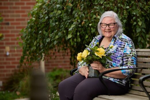 Maureen Foster holding flowers and smiling at the camera.