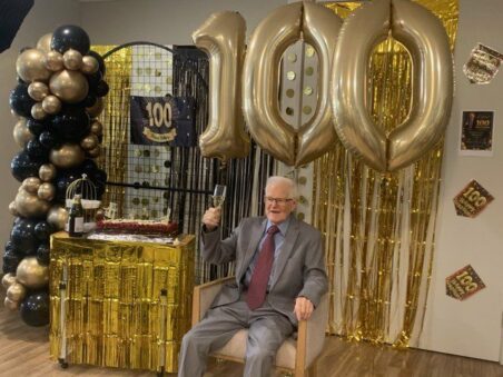 Resident Bruce is photographed at his 100th birthday party, with balloons in the background