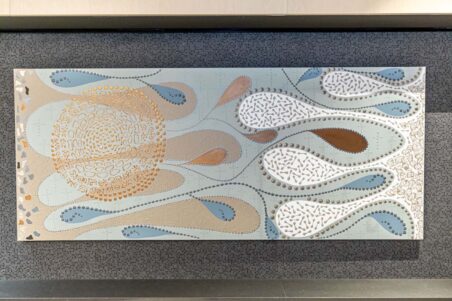 Abstract decorative wall artwork featuring flowing organic shapes in soft blue, beige, white and brown tones. Raised textured patterns, dotted lines and circular motifs create a nature-inspired design mounted on a dark textured wall.