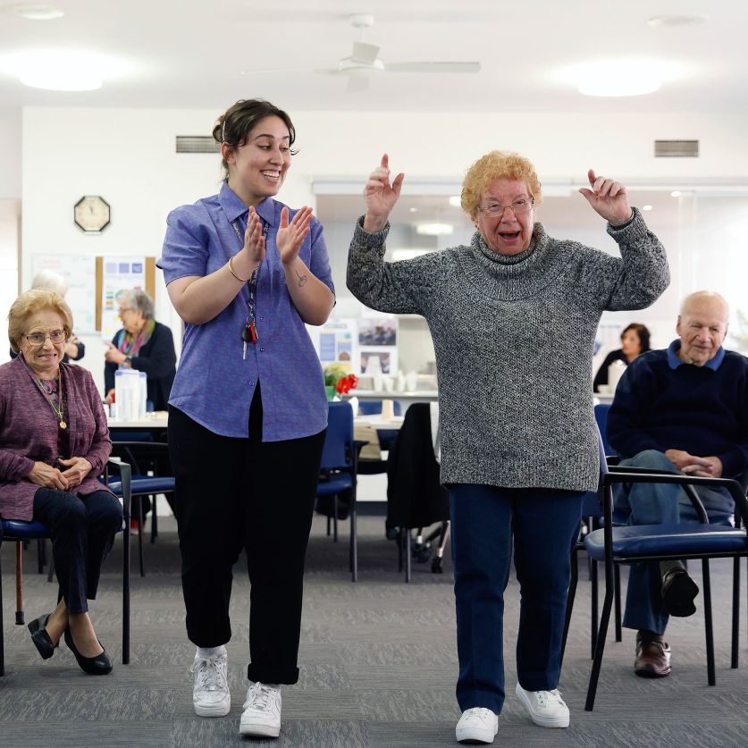 Social connections customer and staff member are pictured dancing together.